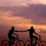 Relationship - woman on bike reaching for man's hand behind her also on bike
