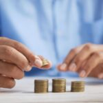 Budget - a person stacking coins on top of a table