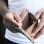 Debt - person holding brown leather bifold wallet