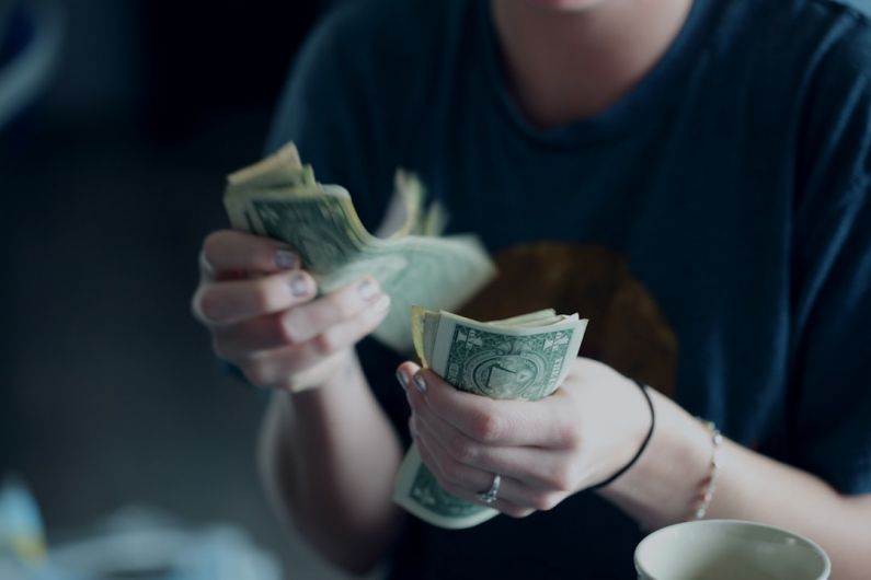 Income - focus photography of person counting dollar banknotes