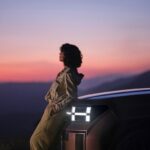 Electric Vehicles - a woman sitting on the hood of a car