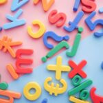 Language - a pile of plastic letters and numbers on a pink and blue background
