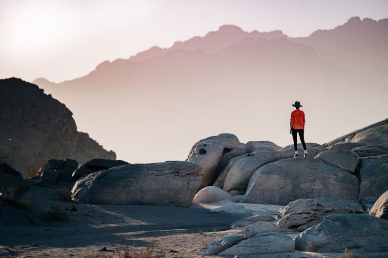 Travel - a person standing on top of a large rock