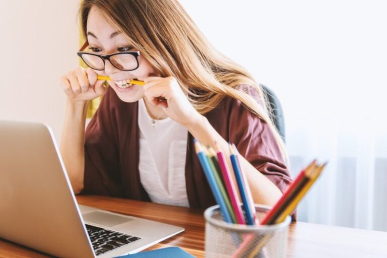 Stress - woman biting pencil while sitting on chair in front of computer during daytime
