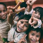 Children - five children smiling while doing peace hand sign