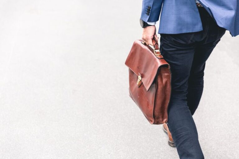 Work - person walking holding brown leather bag