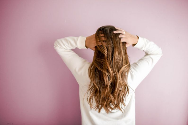 Hair - woman in white long-sleeved shirt standing in front of pink wall