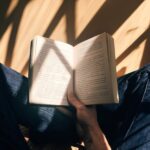 Reading - person holding book sitting on brown surface